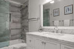 This stunning bathroom features a modern design with a marble countertop and white cabinetry, creating a clean and elegant look.