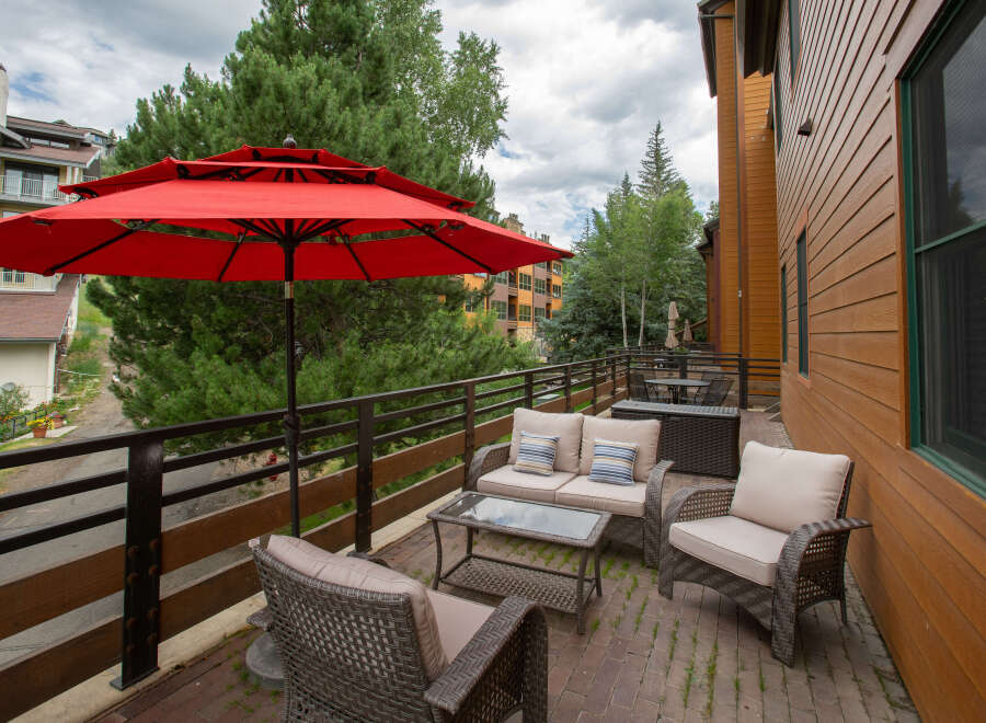 Enjoy the outdoors in style with this beautiful patio space! Featuring comfortable seating, a stylish glass-top coffee table, and a vibrant red umbrella, this outdoor area is perfect for relaxing or entertaining.