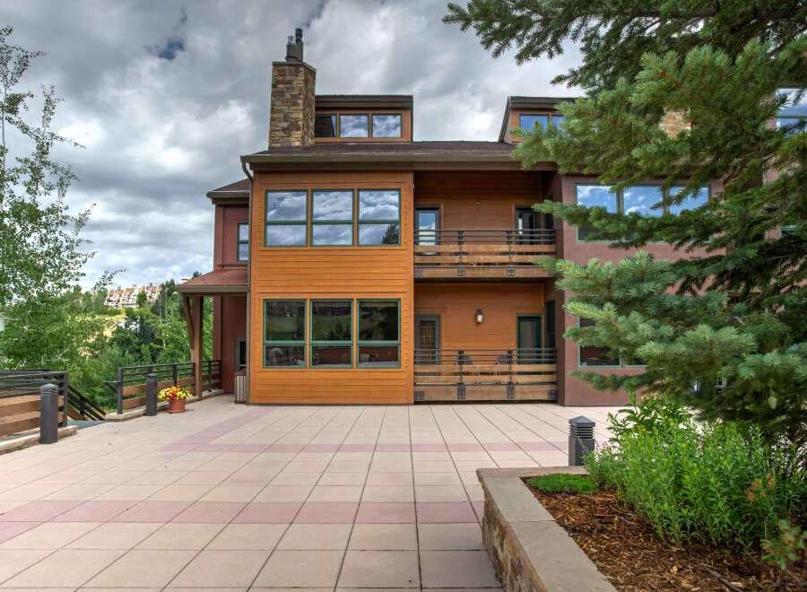This stunning property boasts a modern design with a warm, inviting exterior featuring wood siding and large windows.