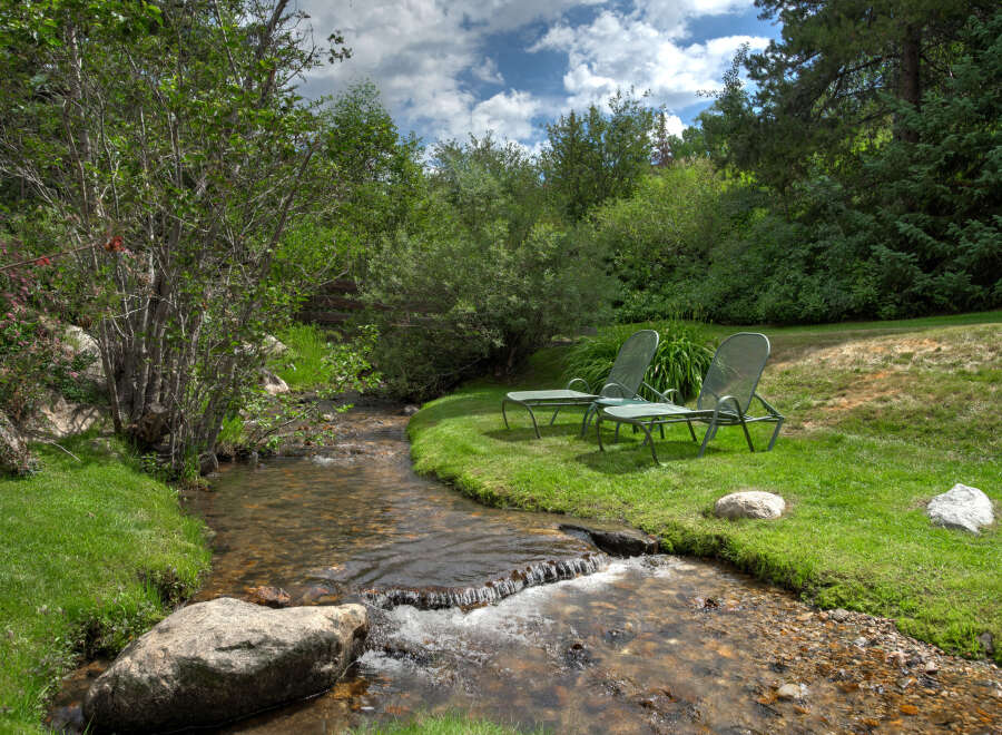 Escape to your own private oasis with this stunning property featuring a serene stream and lush greenery.