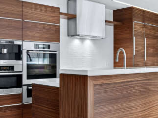 This modern kitchen boasts sleek, dark wood cabinetry and stainless steel appliances, creating a sophisticated and stylish space.