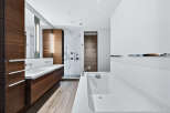 Experience luxury in this modern bathroom, featuring sleek wood cabinetry and a pristine white countertop.