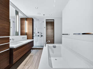 Experience luxury in this modern bathroom, featuring sleek wood cabinetry and a pristine white countertop.