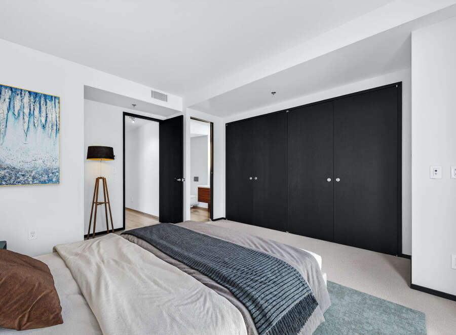 Step into luxury with this stunning bedroom featuring sleek black closet doors and a modern aesthetic.