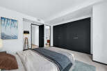 Step into luxury with this stunning bedroom featuring sleek black closet doors and a modern aesthetic.
