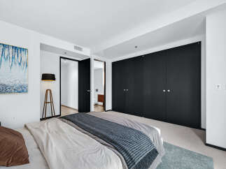 Step into luxury with this stunning bedroom featuring sleek black closet doors and a modern aesthetic.