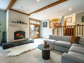 Step into the warmth of this inviting living space, featuring a cozy fireplace and a plush, comfortable sofa.