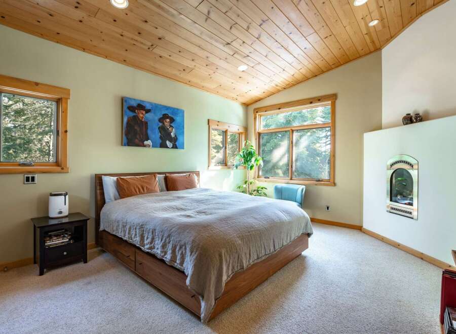 Step into this inviting bedroom, featuring a cozy ambiance with its wooden ceiling and neutral color palette.