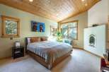 Step into this inviting bedroom, featuring a cozy ambiance with its wooden ceiling and neutral color palette.