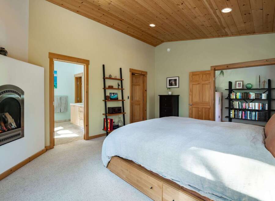 This stunning bedroom boasts a warm and inviting atmosphere with its wooden ceiling and cozy fireplace.