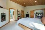 This stunning bedroom boasts a warm and inviting atmosphere with its wooden ceiling and cozy fireplace.