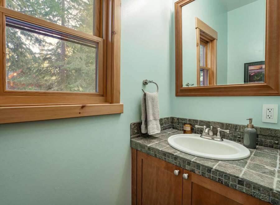 This charming bathroom features a bright, airy design with a beautiful window that offers a stunning view of the surrounding trees.