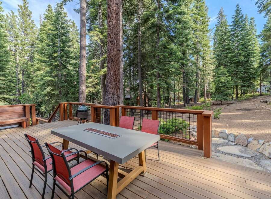 Enjoy outdoor living at its finest on this expansive wooden deck, perfect for entertaining or relaxing amidst a serene forest setting.