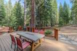 Enjoy outdoor living at its finest on this expansive wooden deck, perfect for entertaining or relaxing amidst a serene forest setting.