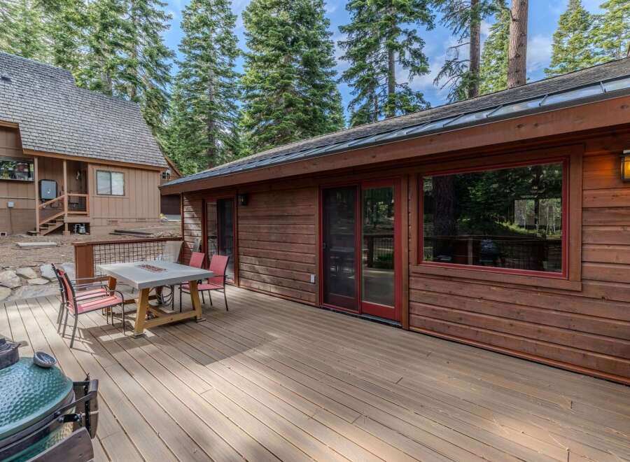 Enjoy outdoor living on this spacious wooden deck, perfect for entertaining or relaxing amidst the tall pine trees.