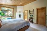 Experience cozy comfort in this inviting bedroom, featuring a charming fireplace and a large window offering serene views of nature.