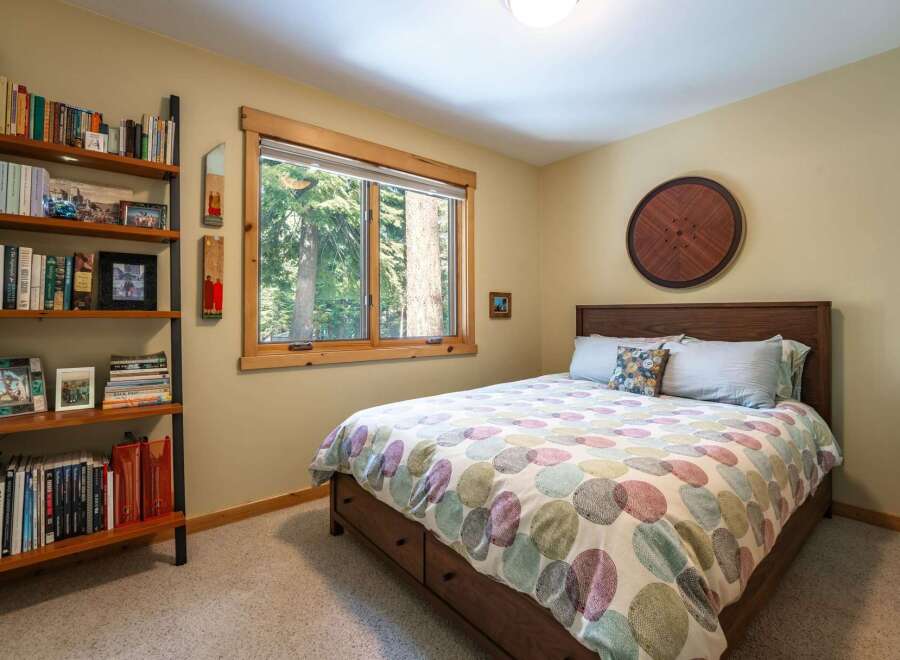 This cozy bedroom features a comfortable queen-size bed with a colorful, circular patterned comforter, perfect for a restful night's sleep.