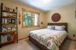 This cozy bedroom features a comfortable queen-size bed with a colorful, circular patterned comforter, perfect for a restful night's sleep.