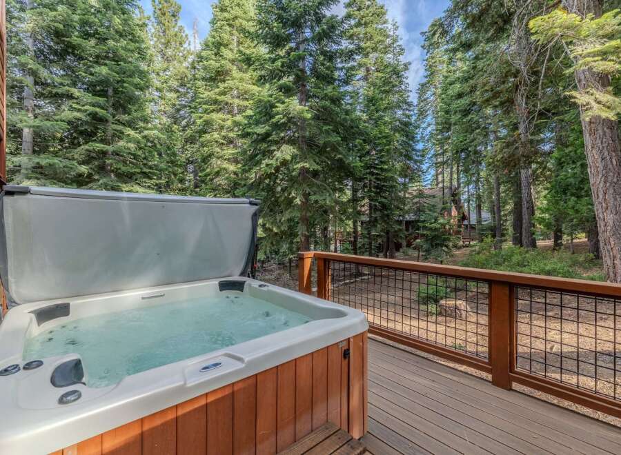 Relax and unwind in this luxurious hot tub, perfectly situated on a spacious wooden deck surrounded by towering pine trees.