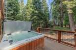 Relax and unwind in this luxurious hot tub, perfectly situated on a spacious wooden deck surrounded by towering pine trees.