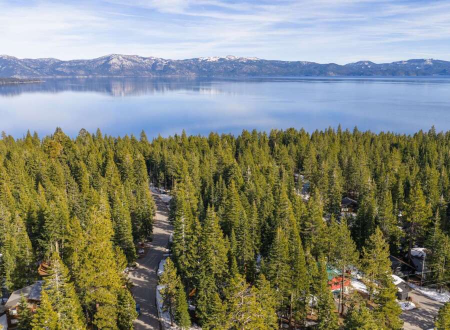 Nestled amidst a dense forest of evergreen trees, this property offers a serene retreat with stunning views of a vast, tranquil lake and snow-capped mountains in the distance.