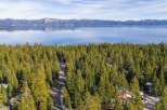 Nestled amidst a dense forest of evergreen trees, this property offers a serene retreat with stunning views of a vast, tranquil lake and snow-capped mountains in the distance.