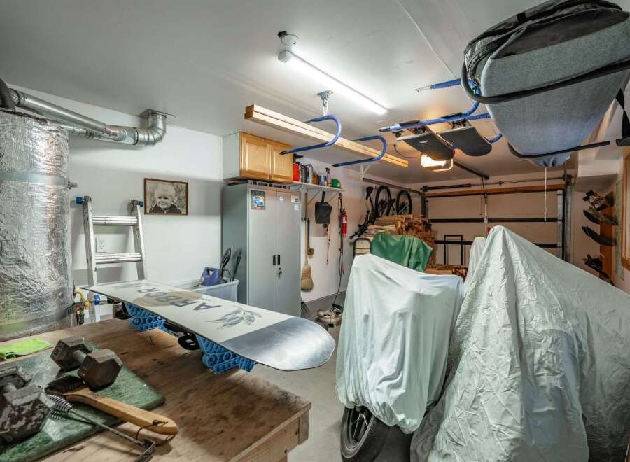 This spacious garage offers ample storage solutions, including overhead racks perfect for seasonal gear like snowboards.