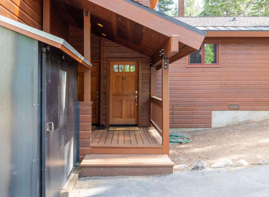 Experience rustic charm with this inviting wooden cabin exterior, featuring a welcoming covered porch and a classic wooden front door.
