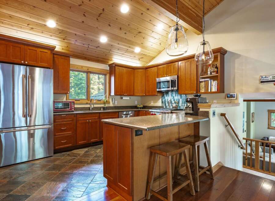 This spacious kitchen boasts rich cherry wood cabinetry and a vaulted, wood-paneled ceiling with recessed lighting.