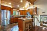 This spacious kitchen boasts rich cherry wood cabinetry and a vaulted, wood-paneled ceiling with recessed lighting.