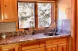 This charming kitchen features beautiful light wood cabinetry, complemented by a speckled granite countertop and a light blue subway tile backsplash.