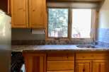 Discover this charming kitchen featuring warm, natural wood cabinetry and a spacious granite countertop.