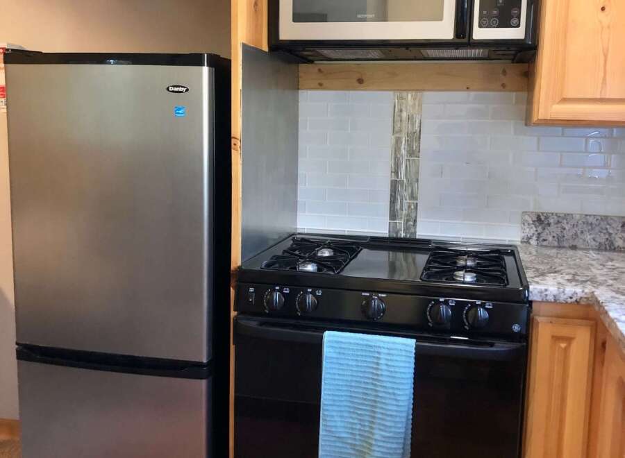 This charming kitchen features a stainless steel Danby refrigerator and a black gas range, perfect for any home chef.