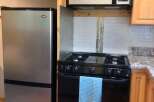 This charming kitchen features a stainless steel Danby refrigerator and a black gas range, perfect for any home chef.