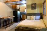 Discover this charming studio apartment featuring a cozy sleeping area with a comfortable bed and decorative pillows.