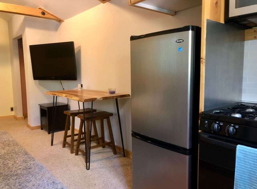 This compact living space features a modern stainless steel refrigerator and a sleek stovetop, perfect for preparing meals.