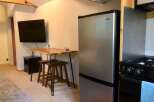 This compact living space features a modern stainless steel refrigerator and a sleek stovetop, perfect for preparing meals.