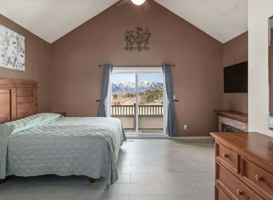 This stunning bedroom offers a serene retreat with breathtaking mountain views visible through the large sliding glass doors.