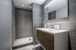 This modern bathroom features a sleek design with gray tiled walls and a stylish vanity.