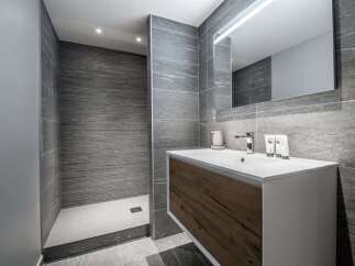 This modern bathroom features a sleek design with gray tiled walls and a stylish vanity.