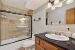 This charming bathroom features a rustic design with a tiled shower and a sleek black countertop.