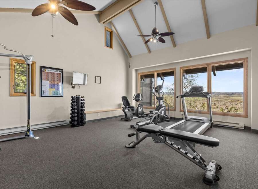 This spacious home gym offers a variety of workout equipment, including a treadmill, elliptical, and weight bench.