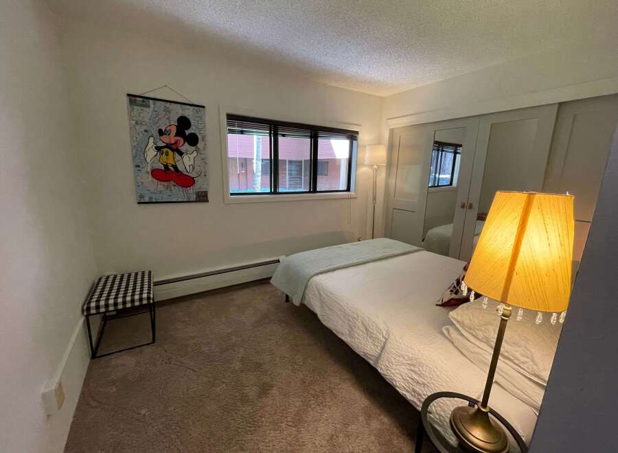 This cozy bedroom features a comfortable bed with a light blue blanket and a stylish lamp.