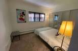 This cozy bedroom features a comfortable bed with a light blue blanket and a stylish lamp.