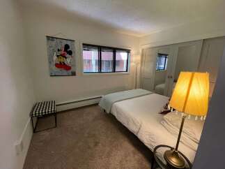 This cozy bedroom features a comfortable bed with a light blue blanket and a stylish lamp.