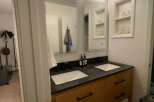 This modern bathroom features a sleek double vanity with a dark countertop and wooden cabinets, offering ample storage space.