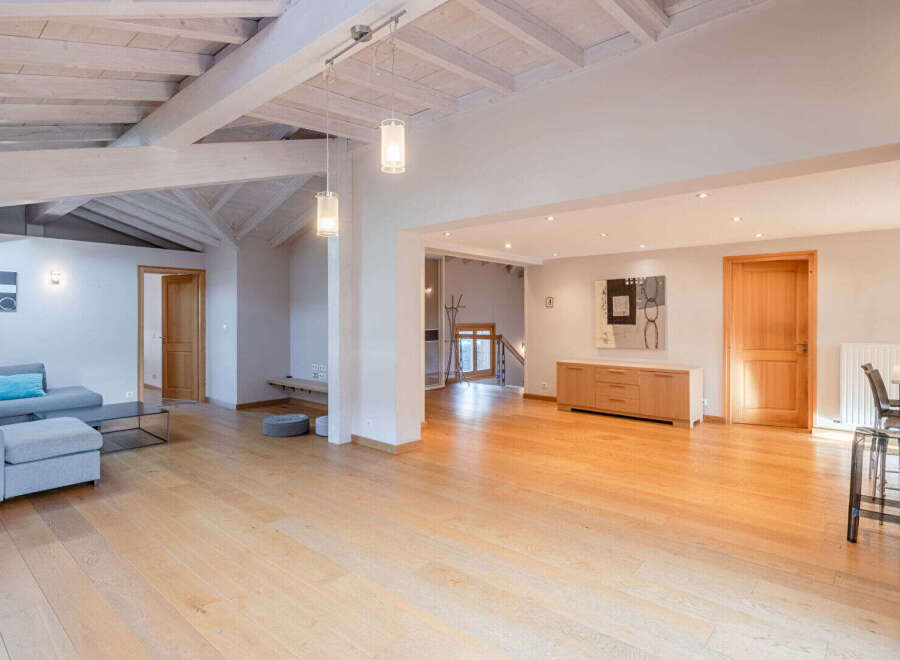This stunning property boasts a spacious, open-plan living area with beautiful wooden floors and exposed beams, creating a warm and inviting atmosphere.