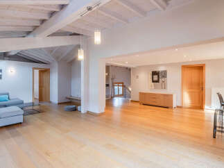 This stunning property boasts a spacious, open-plan living area with beautiful wooden floors and exposed beams, creating a warm and inviting atmosphere.