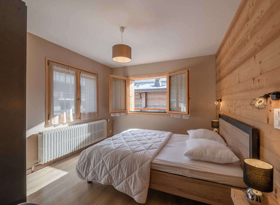 This cozy bedroom features a warm wooden accent wall and a comfortable bed, perfect for a relaxing retreat.