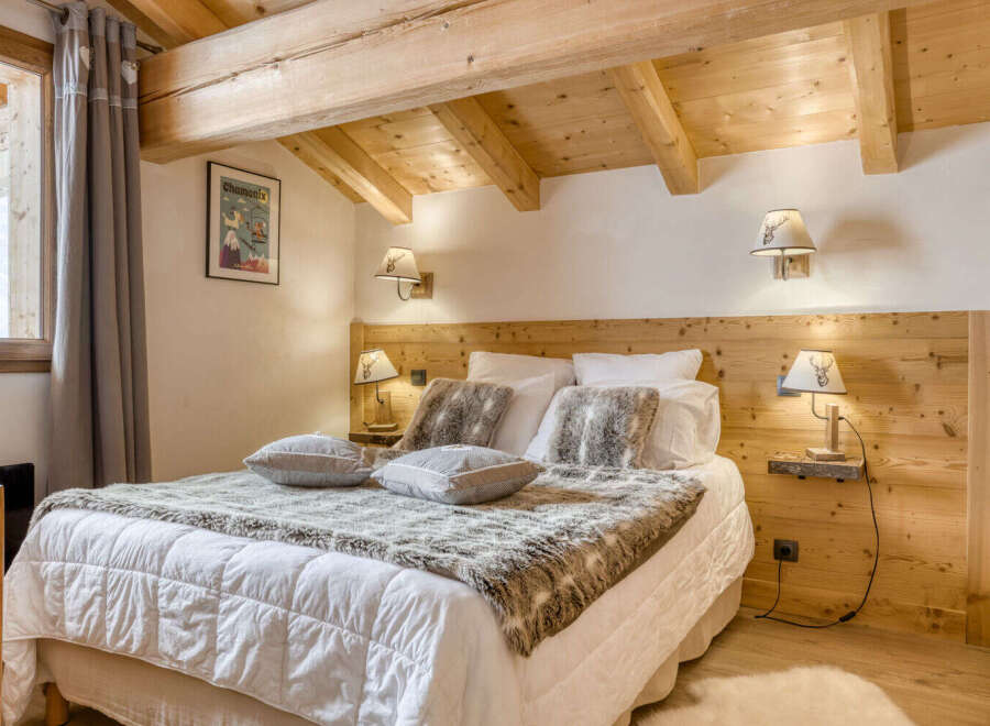 Experience the charm of this cozy bedroom featuring a rustic wooden headboard and ceiling beams, creating a warm and inviting atmosphere.